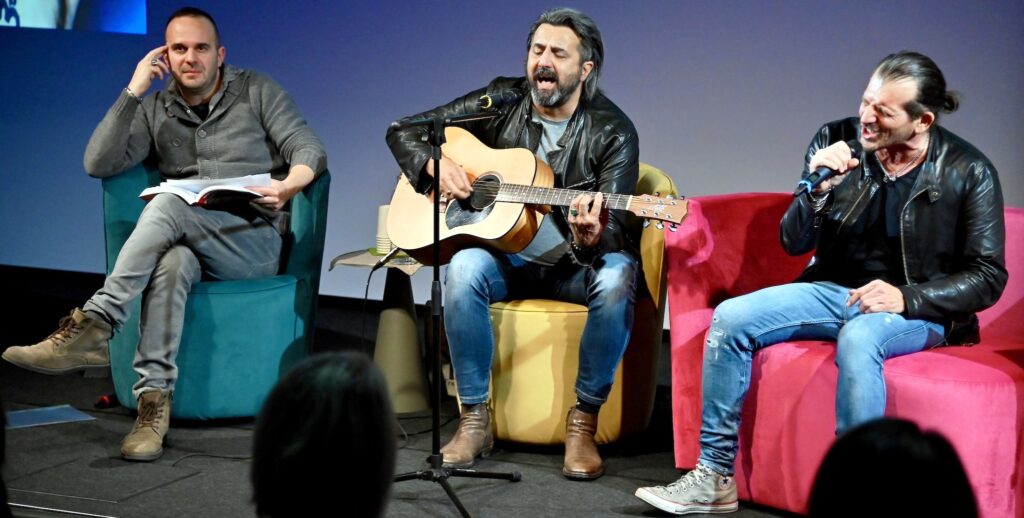 Omar Pedrini accompagna con la chitarra la voce di Davide Apollo per eseguire alcuni dei suoi brani più famosi. A sinistra il coautore di "Cane sciolto" Federico Scarioni, che ha letto alcune pagine del libro 